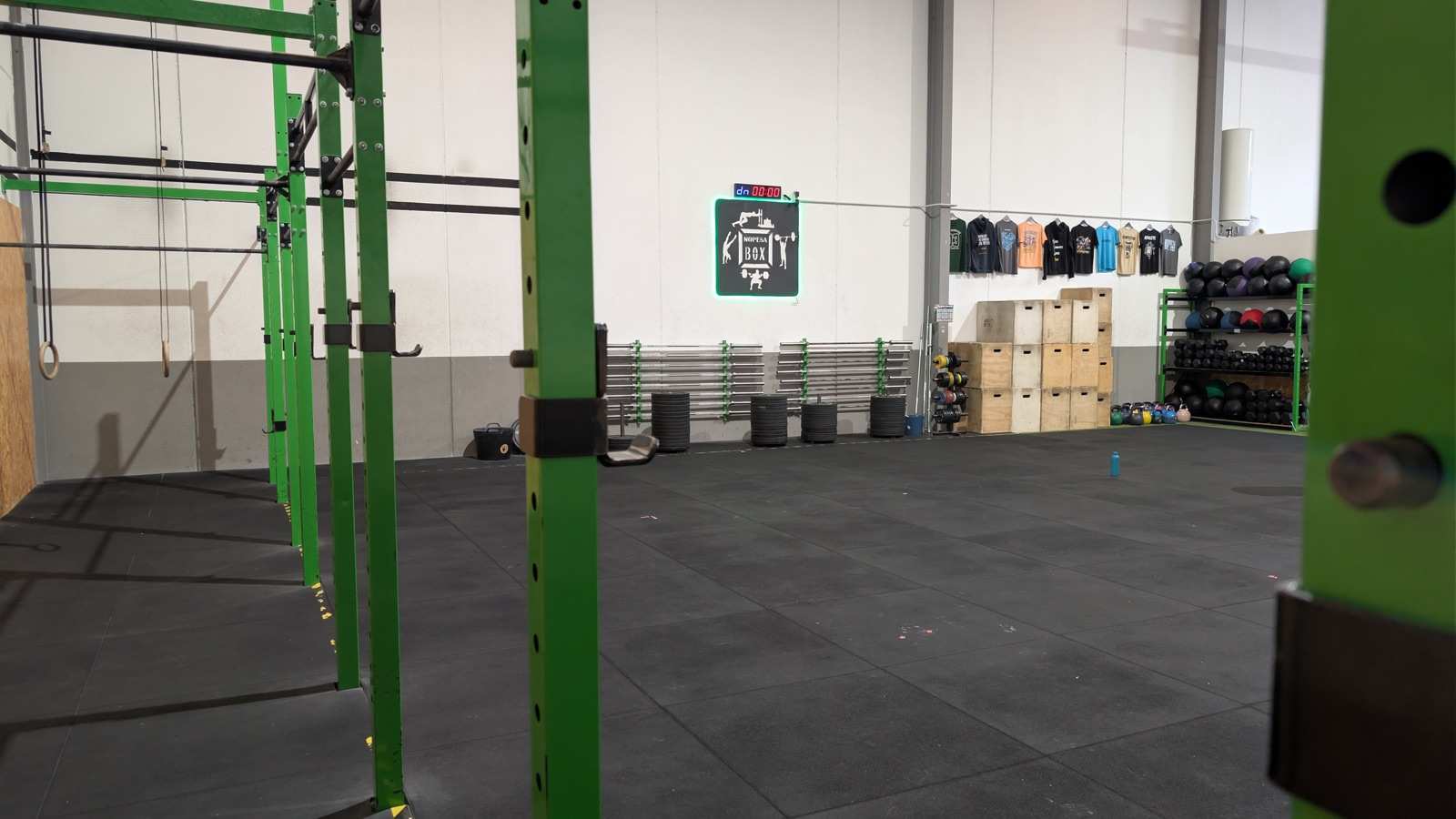 Interior vacío del box NOPESA Banyeres, con el logo en la pared y los racks verdes